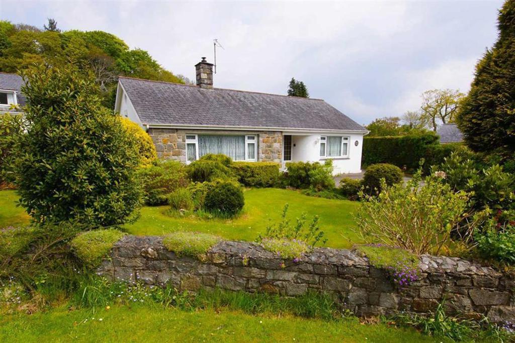 a house with a stone wall in front of a yard at Greenacres in Llanbedrog