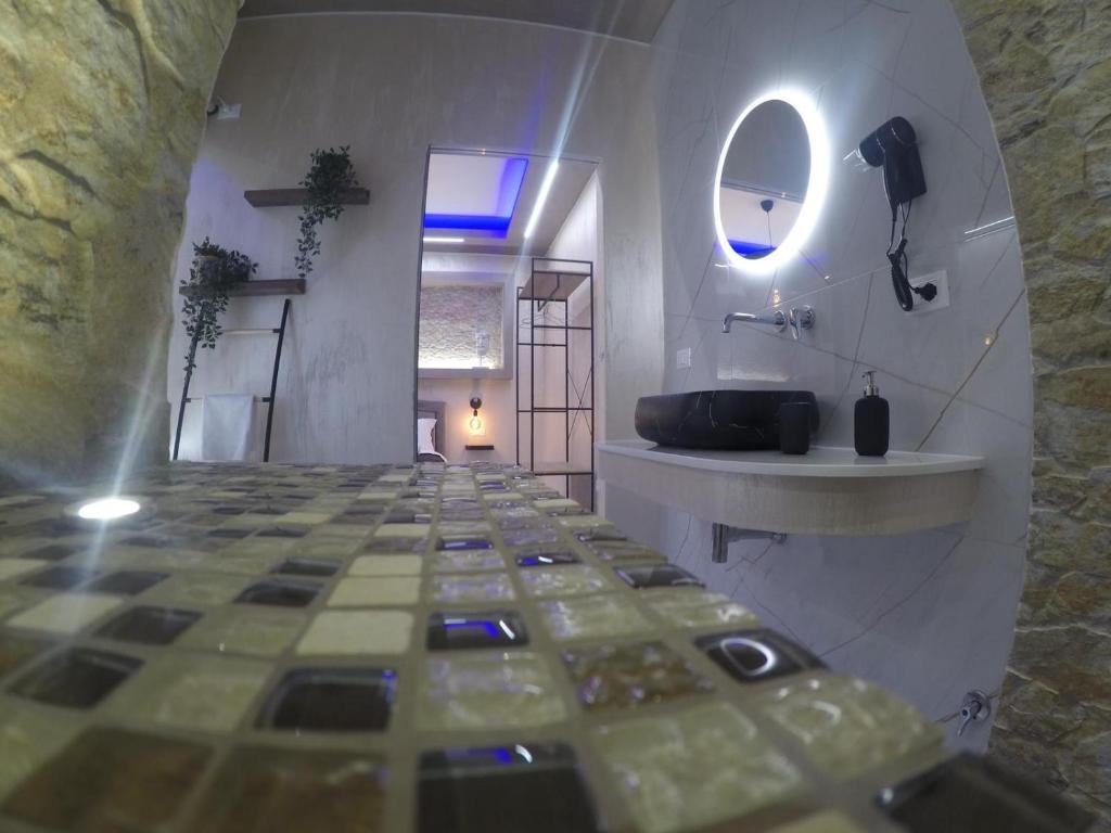 bagno con pavimento piastrellato e lavandino di LE CAMERE Luxury Rooms SIRACUSA a Siracusa