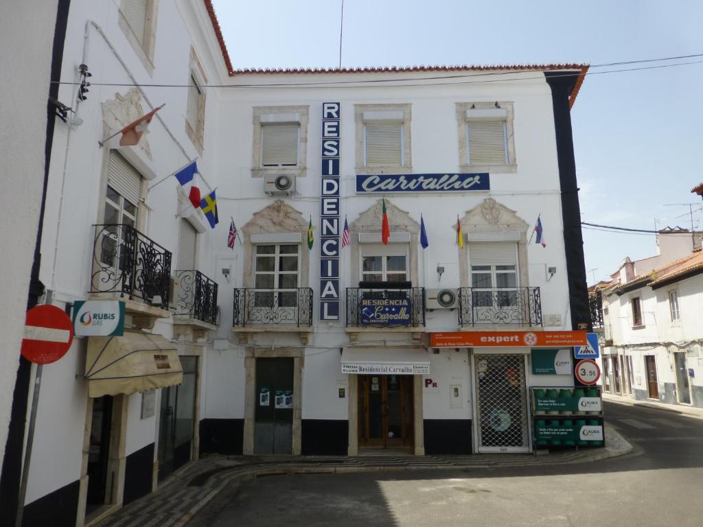 ein weißes Gebäude mit einem Schild auf einer Straße in der Unterkunft Residencial Carvalho in Estremoz