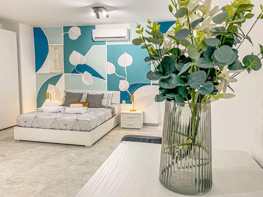 - un salon avec un lit et un vase de fleurs dans l'établissement Designer Duplex Penthouse in Floriana, à Il-Furjana