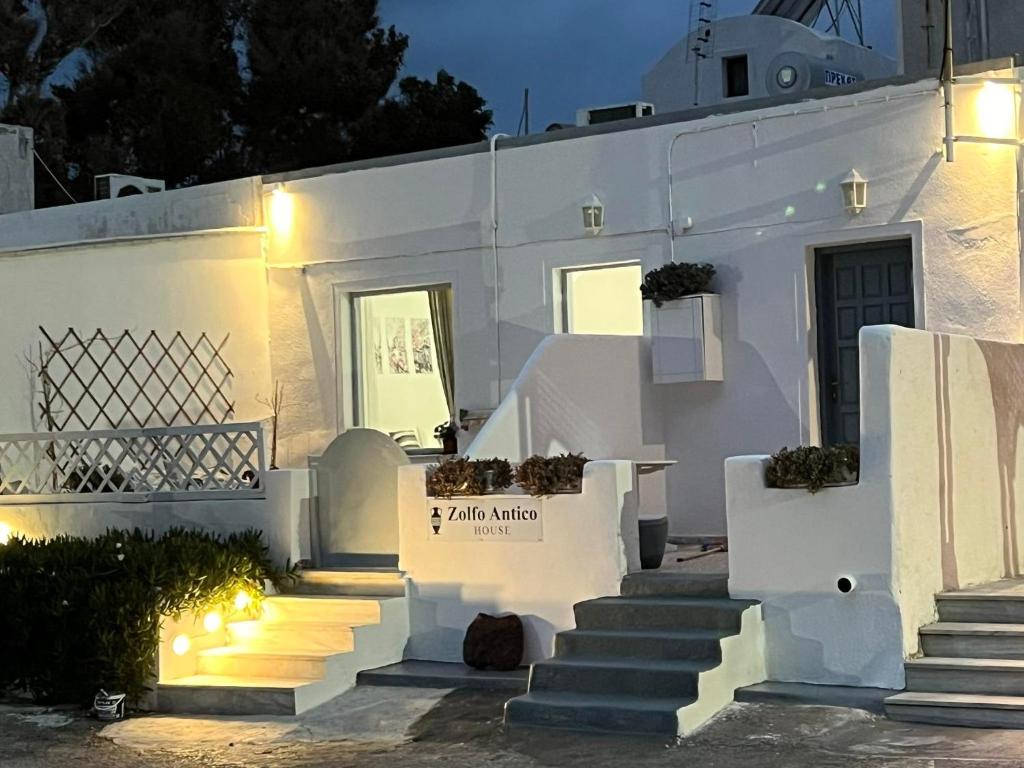 a white house with stairs in front of it at Zolfo Antico Beach Apartment Perissa in Perissa