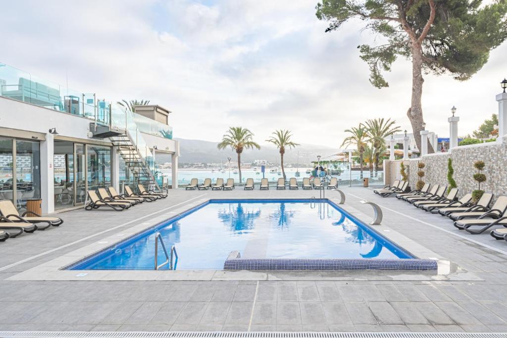 a swimming pool with lounge chairs and a resort at Seramar Hotel Comodoro Playa in Palmanova