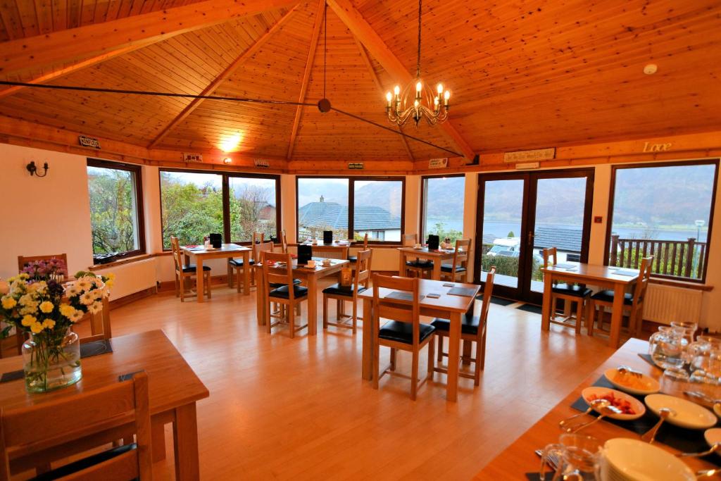 un comedor con mesas, sillas y ventanas en Lochview House, en Fort William