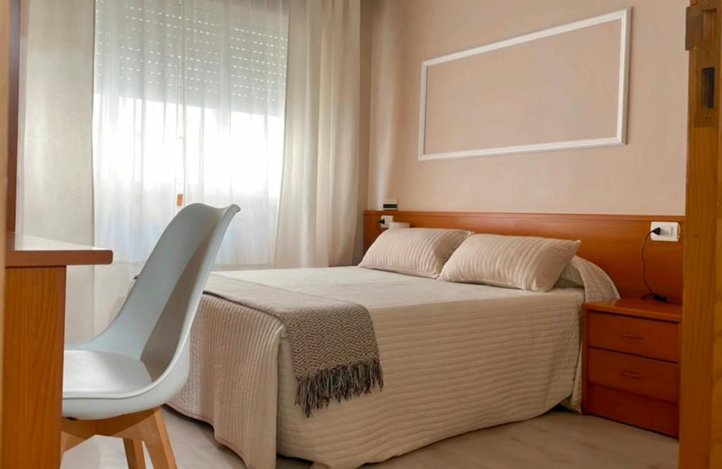 a bedroom with a bed and a chair and a window at Casa Pazos, Pedrafita do Cebreiro in Piedrafita
