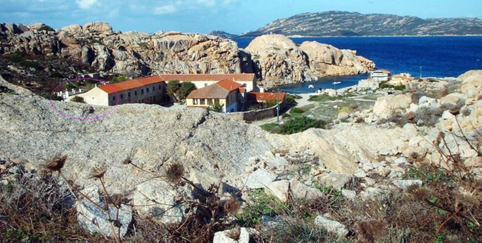 a group of buildings on a rocky hill with the ocean at La Maddalena Apartment in La Maddalena