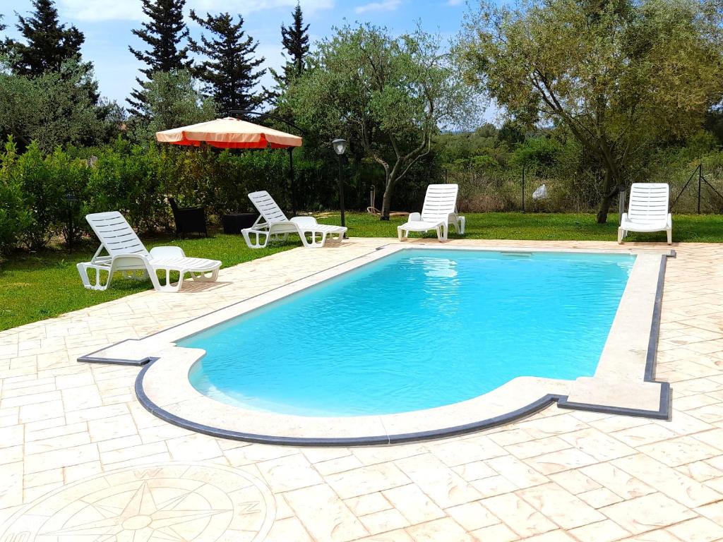 una piscina con due sedie e un ombrellone di 3 bedrooms villa with private pool enclosed garden and wifi at Noto a Noto