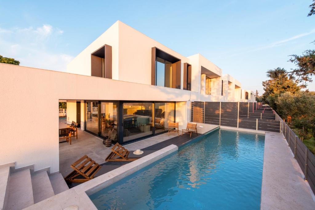 a house with a swimming pool in front of it at Serene seafront villas in Nea Iraklia