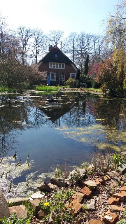 une maison assise au-dessus d'un étang en face d'une maison dans l'établissement De Geheime Tuin - Uitzicht, à Epe