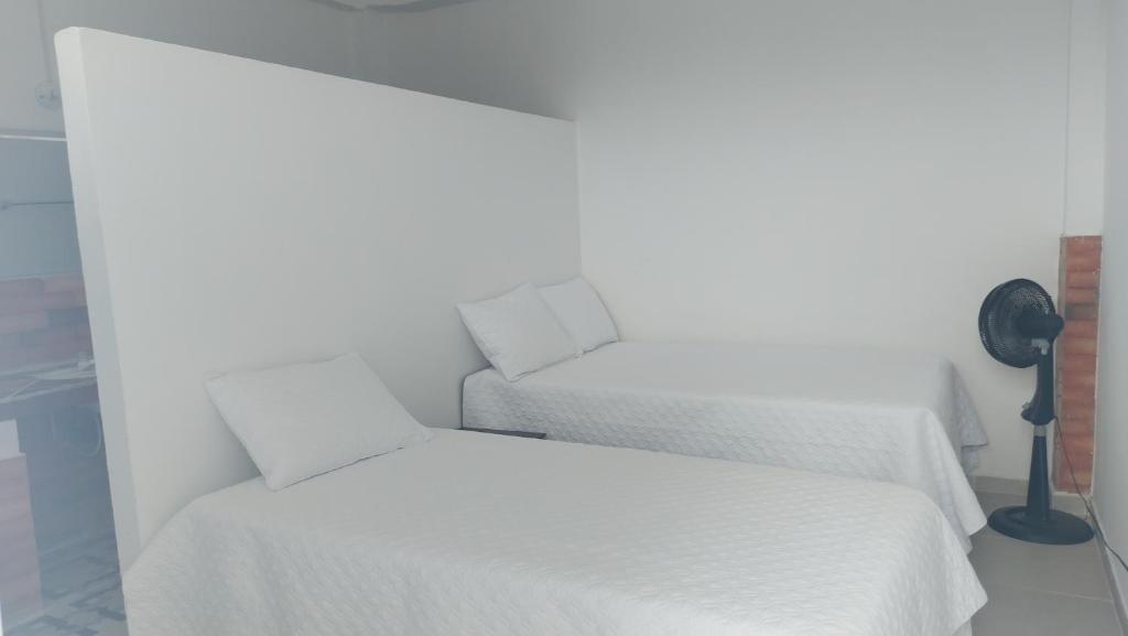 1 dormitorio con 2 camas con sábanas blancas y ventilador en Mangüeña Alojamiento Rural en Santa Rosalía de Guagua
