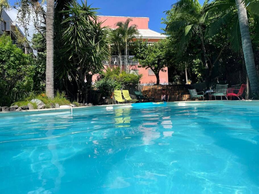a large swimming pool with blue water and palm trees at Villa KazAlizés avec Piscine et Jardin Saint Leu in Saint-Leu
