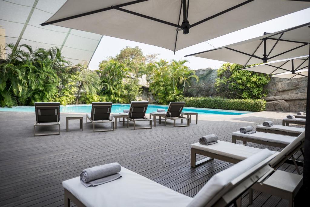 un patio con sillas, una sombrilla y una piscina en Hotel Trópico, en Luanda