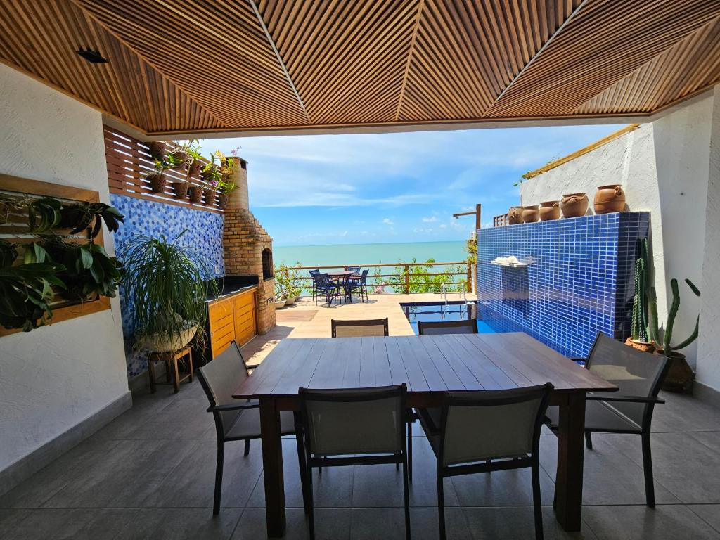 a wooden table and chairs on a balcony with the ocean at A CASA FORMOSA in Baía Formosa