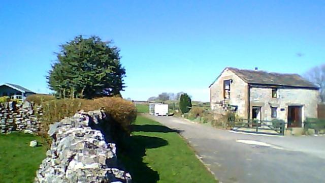una pared de piedra junto a una casa y una carretera en Old Coach House en Matlock
