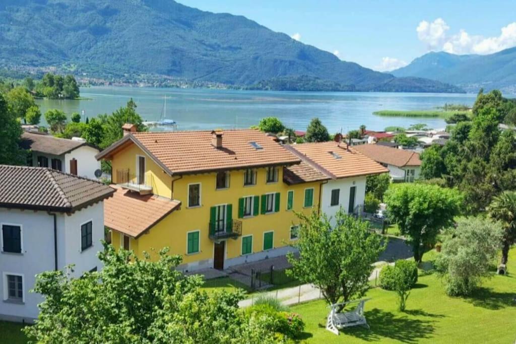 a yellow house with a view of a lake at Casa Mimosa - appartamento vacanze sul Lago di Como in Sorico