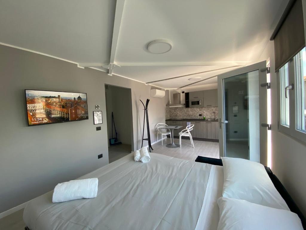 a bedroom with a large white bed and a kitchen at Corridoni33 - Immobili e Soluzioni Rent in Bergamo