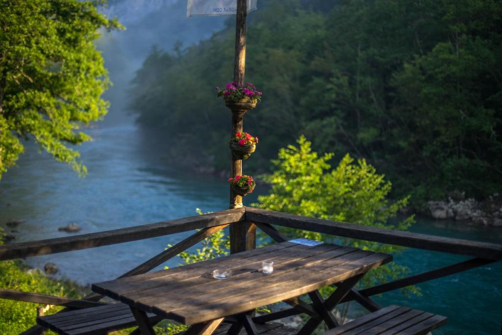 een houten tafel met bloemen op het naast een rivier bij GRAB ethno village and camp in Šćepan-Polje