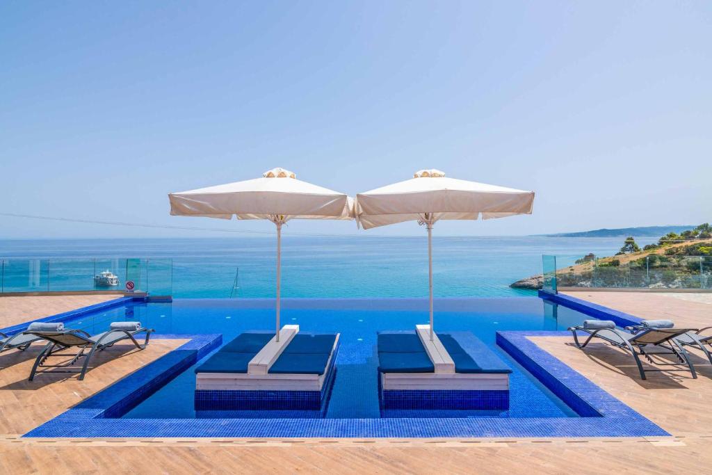 a swimming pool with two chairs and an umbrella at Villa Orient Platinum in Skinária