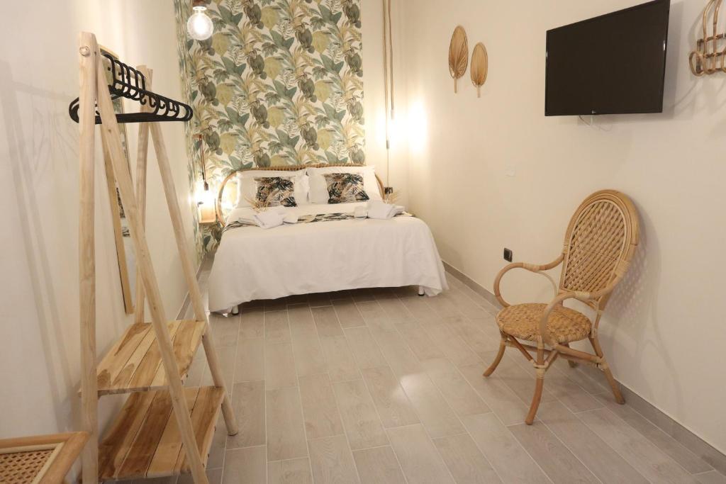sypialnia z łóżkiem, telewizorem i krzesłem w obiekcie Sophia Apartments w mieście Avola