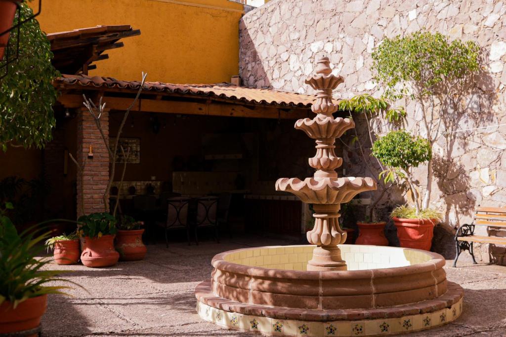a fountain in the courtyard of a house with potted plants at Casa Amarilla in Guanajuato