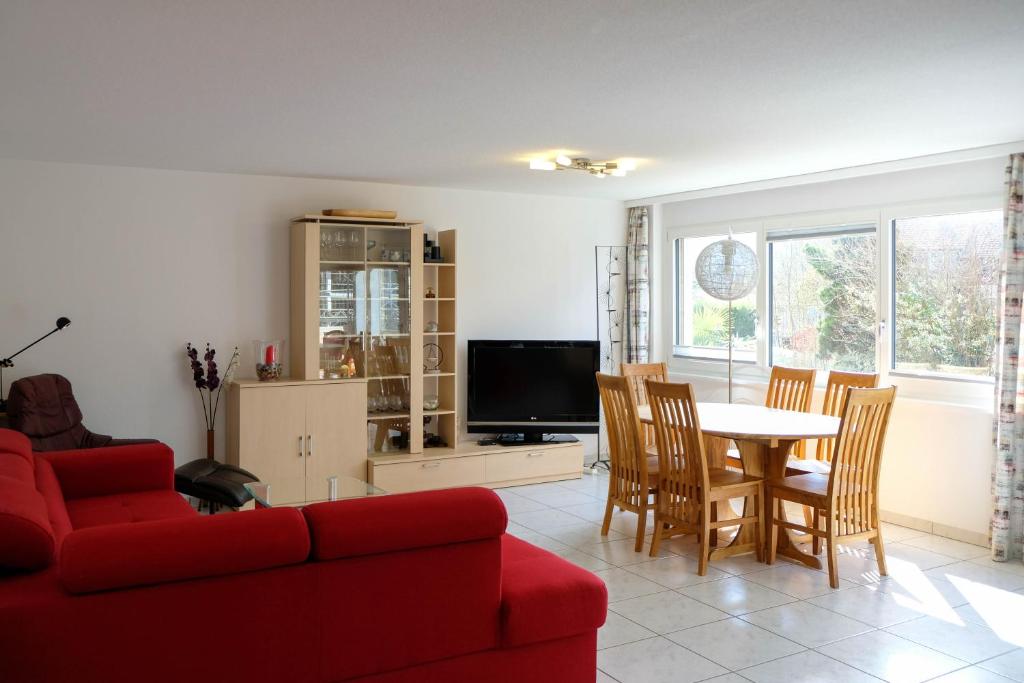 a living room with a red couch and a table and chairs at Susy's Place in Spiez