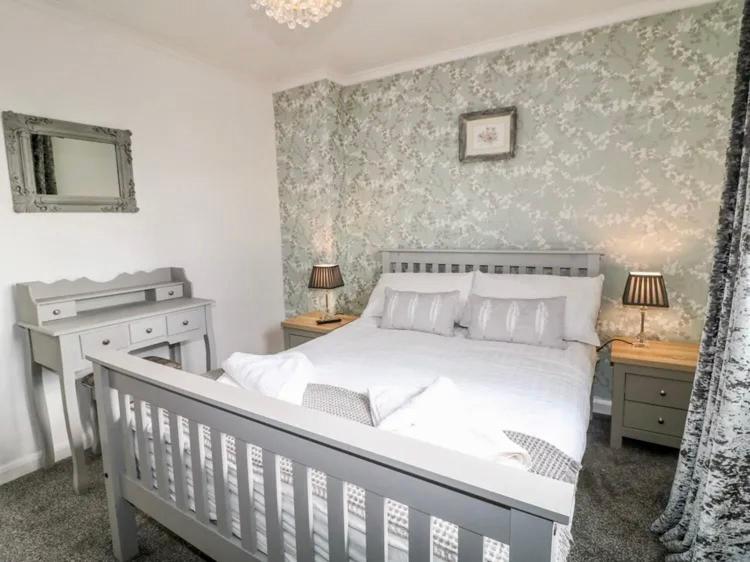 a bedroom with a white bed and two tables and a mirror at Hunters Lodge, with parking for one car in Lincoln