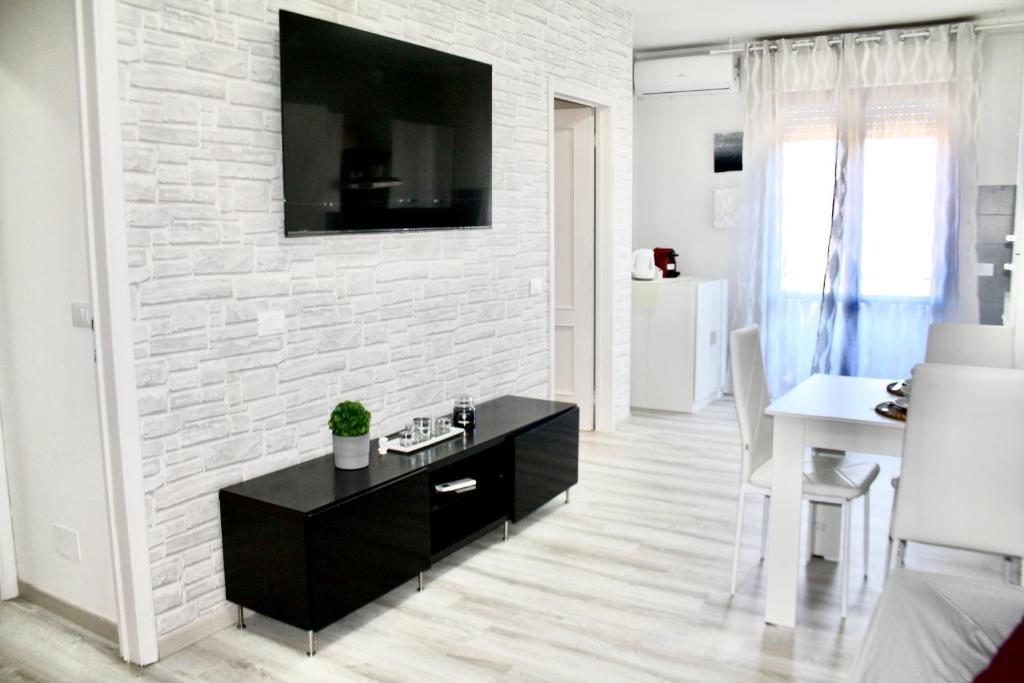un salon avec une télévision sur un mur de briques blanches dans l'établissement Viareggio Deluxe, à Viareggio
