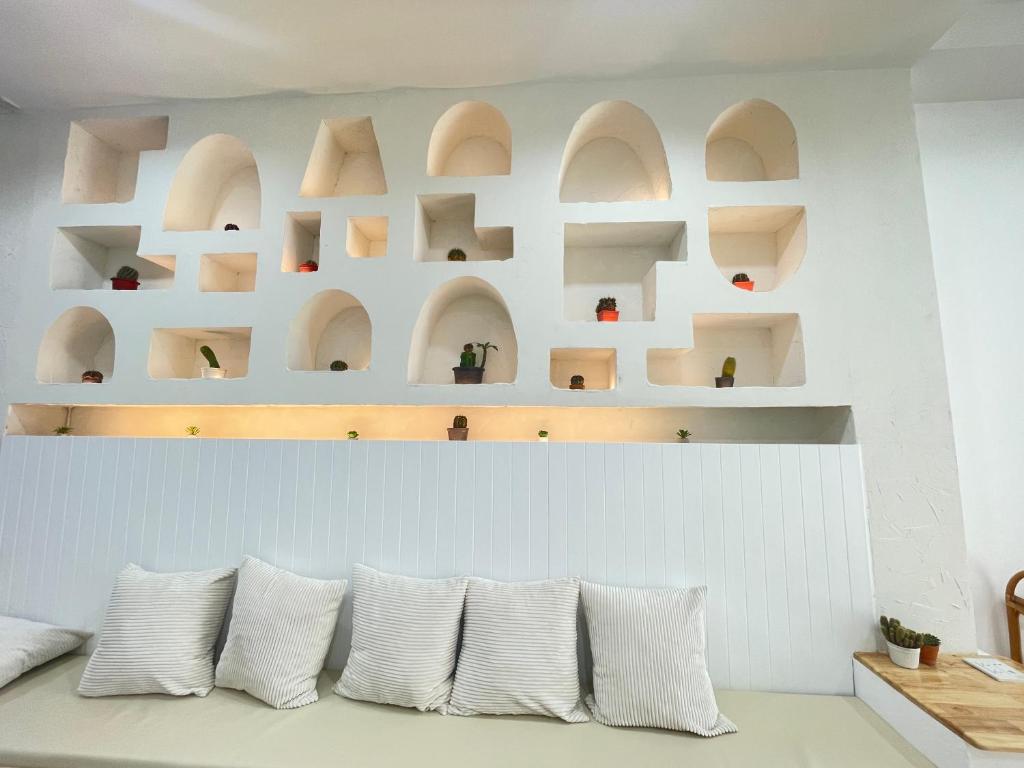 a row of white pillows on a white wall with shelves at มินิมอลโฮลเทล in Ban Khlong Khachen