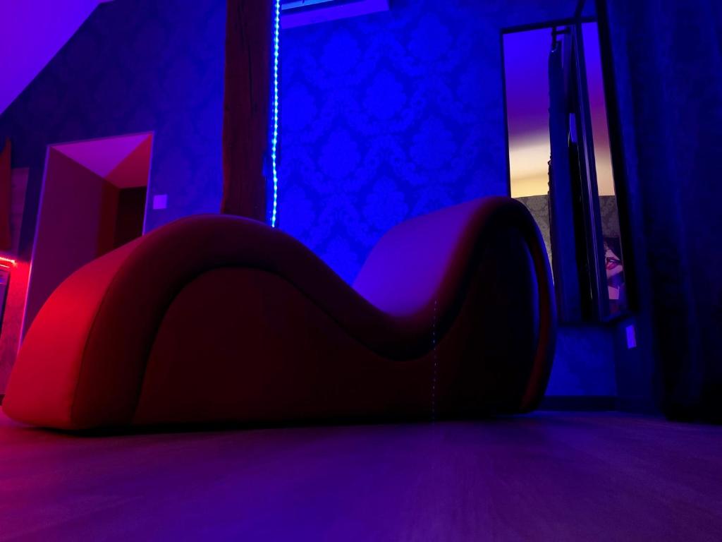un letto in una camera con luci viola e blu di Love room avec jacuzzi privé a Bonnétable