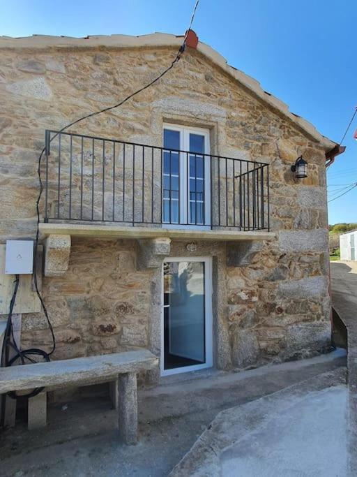 a stone building with a balcony and a bench at Casa con encanto en Laxe in Laxe
