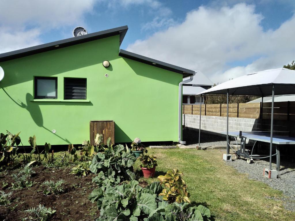 a green house with a garden and an umbrella at l'an dormi vacances in La Plaine des Cafres