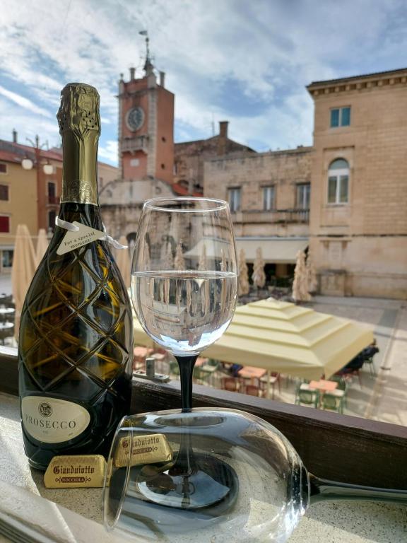 una botella de vino y una copa de vino en una mesa en Apartment Agora, en Zadar