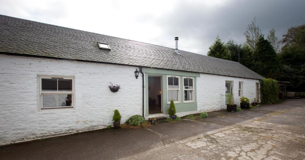 une maison blanche avec une fenêtre et une allée. dans l'établissement The Steading, Back Borland Holiday Cottages, à Stirling