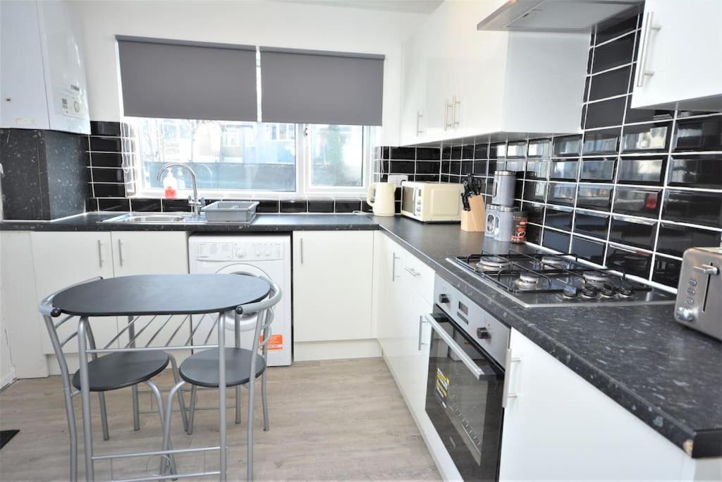 a kitchen with white cabinets and a black counter top at 4 Bedroom House in East London in London