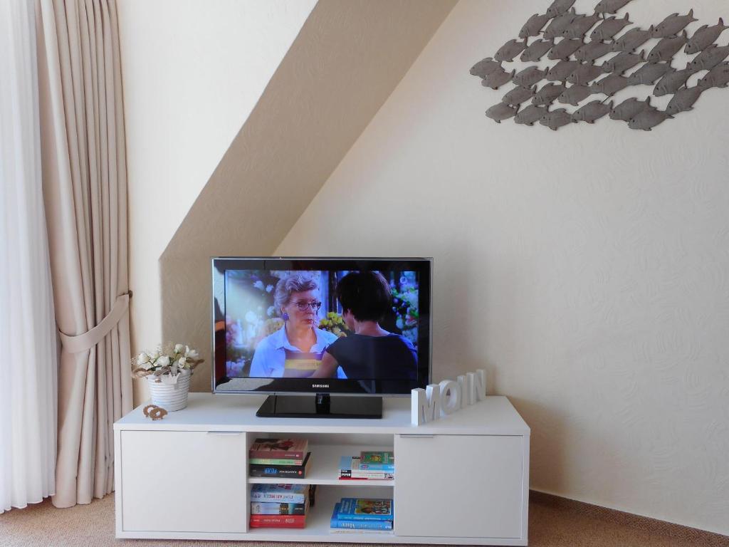 - une télévision installée au-dessus d'un centre de divertissement blanc dans l'établissement Haus-Seeschwalbe-Wohnung-2, à Nieblum