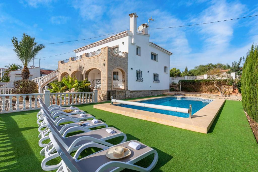 a row of lawn chairs in front of a house at Villa Caleta - PlusHolidays in Calpe