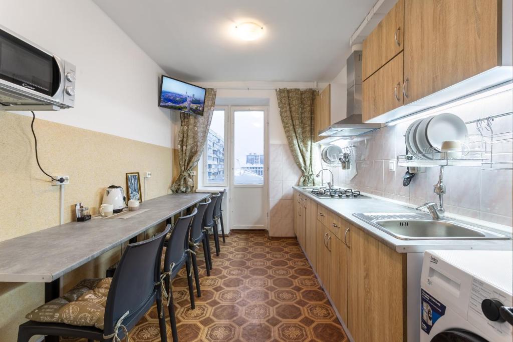 a kitchen with a long counter with chairs and a sink at Хостел єЖитло Щекавиця in Kyiv