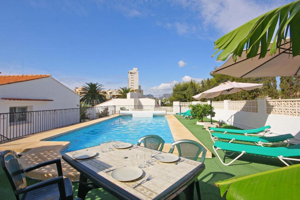 un patio con mesa y sillas junto a una piscina en Villa Calalga - PlusHolidays, en Calpe