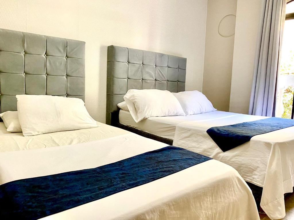 Habitación con 2 camas y sábanas blancas y azules. en Hotel Bahia Suite, en Santa Marta
