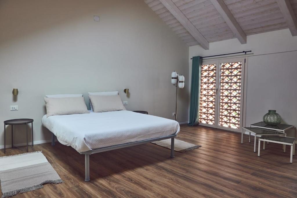 ein weißes Schlafzimmer mit einem Bett und einem großen Fenster in der Unterkunft Cascina cortese in Vigliano d'Asti