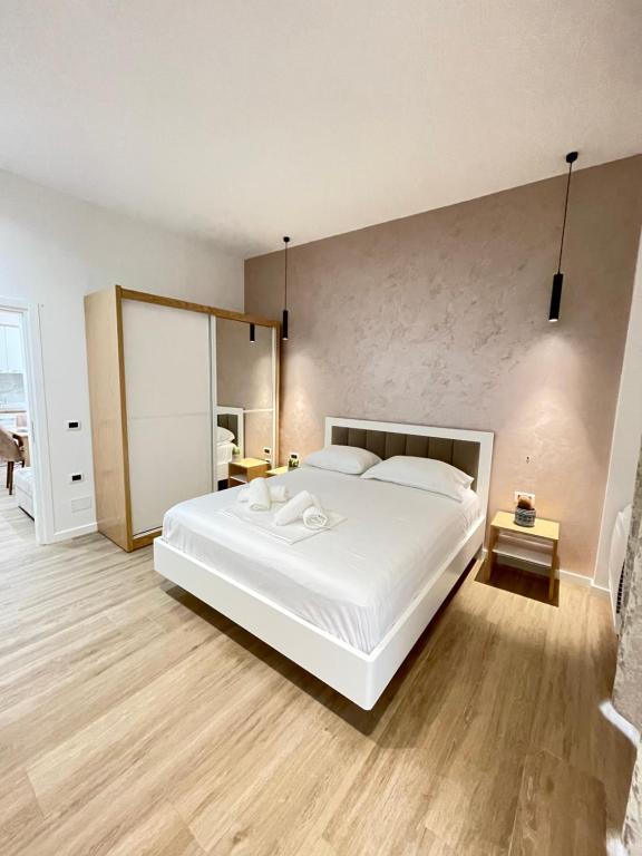 a bedroom with a large white bed and wooden floors at Arial Trinity Suites in Vlorë