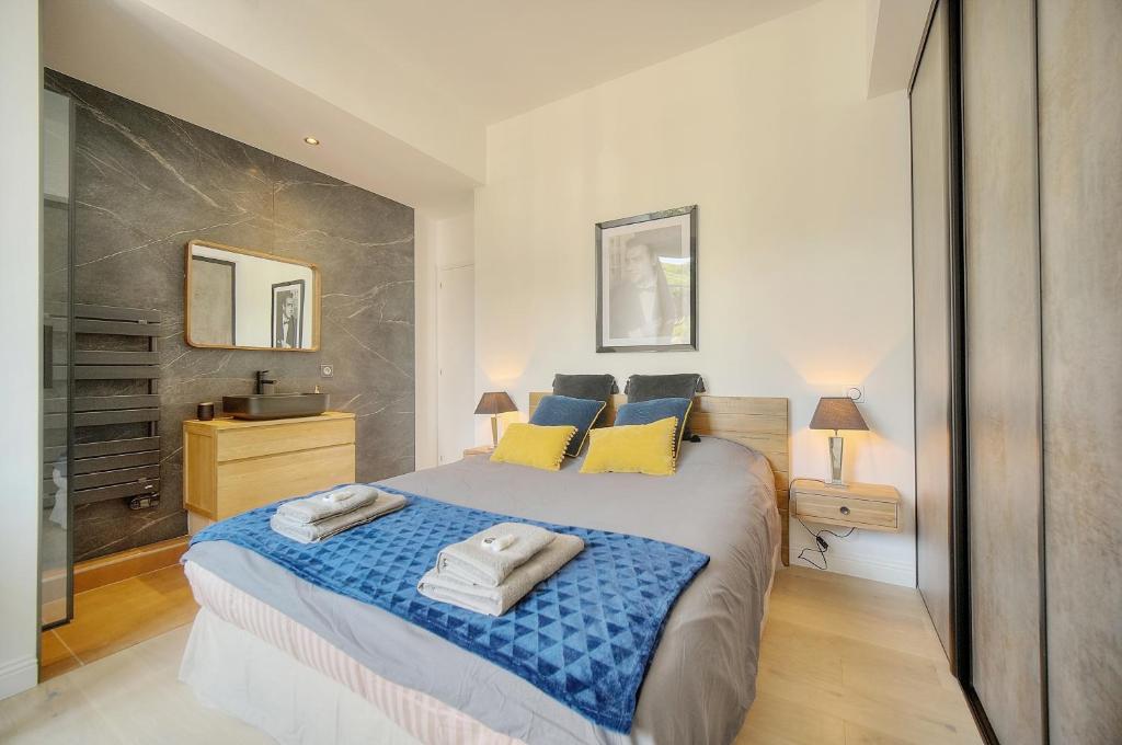 ein Schlafzimmer mit einem großen Bett mit blauen und gelben Kissen in der Unterkunft STANDING - NEUF - Croisette- Palais des festivals - 6 pers -3 chbres in Cannes