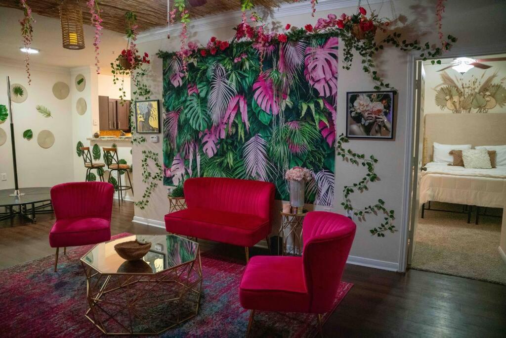 a living room with red chairs and a wall with plants at Pink Tulum Houston 2min from Galleria in Houston
