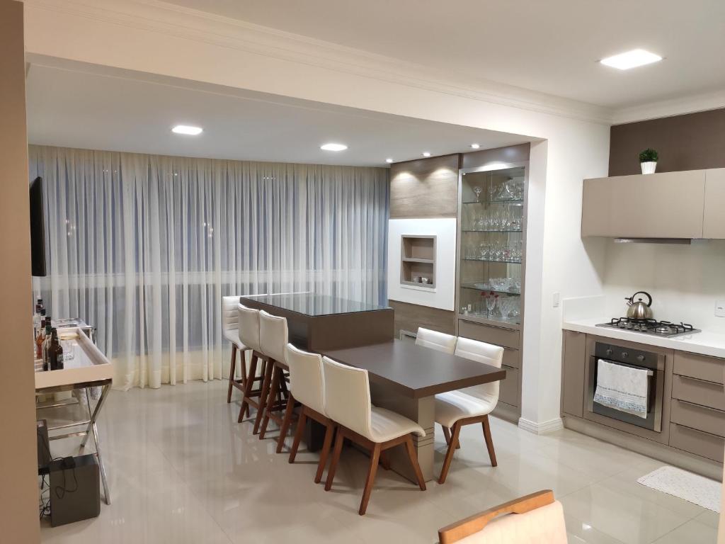 - une cuisine et une salle à manger avec une table et des chaises dans l'établissement Apartamento luxo Meia Praia, à Itapema