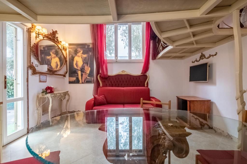 ein Wohnzimmer mit einem roten Stuhl und einem Glastisch in der Unterkunft MERLO 1 free park & wifi in Pisa