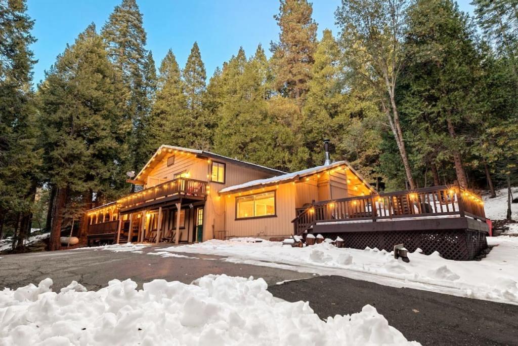 une maison dans les bois avec de la neige autour dans l'établissement Sugarpine Trailhead Lodge at Lewis Creek Upper Trailhead just 7 miles from Yosemite, à Oakhurst