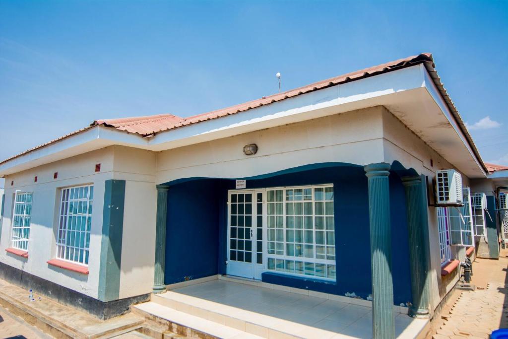 a blue and white house with a blue door at Cherries Egul Lodges in Lilongwe