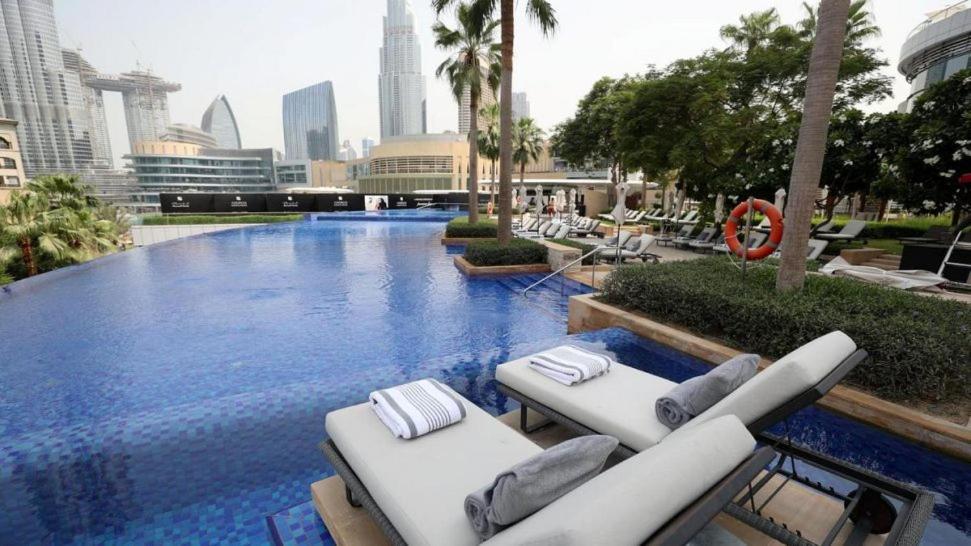 a large swimming pool with lounge chairs in a city at Elite Downtown Residences - Paradise View in Dubai