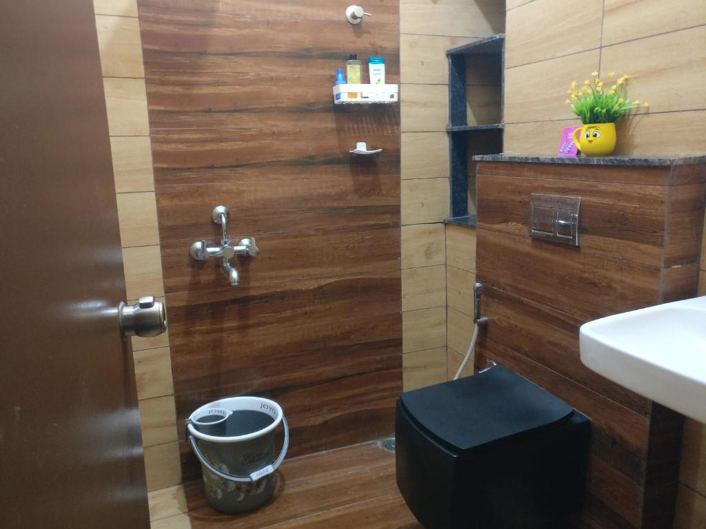 een badkamer met een houten muur naast een toilet bij SindooRa in Mysore