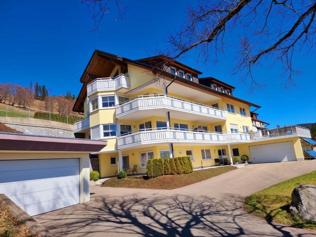 ein großes gelbes Haus mit weißen Balkonen und einer Auffahrt in der Unterkunft Deluxe Ferienwohnung Schwarzwald, Haus Sonnenschein in Todtnau