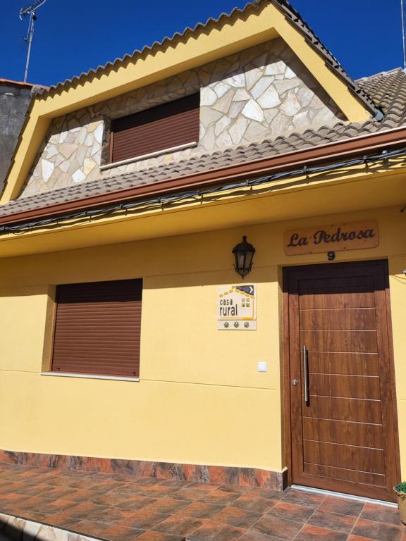 a yellow house with a wooden garage door at La Pedrosa Casa Rural in Camarzana de Tera